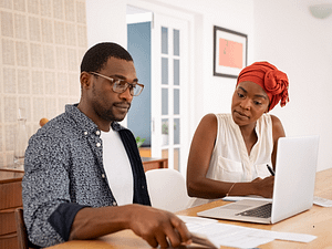 A couple reviewing home expenses and bills at a table, representing the financial aspects of homeownership.